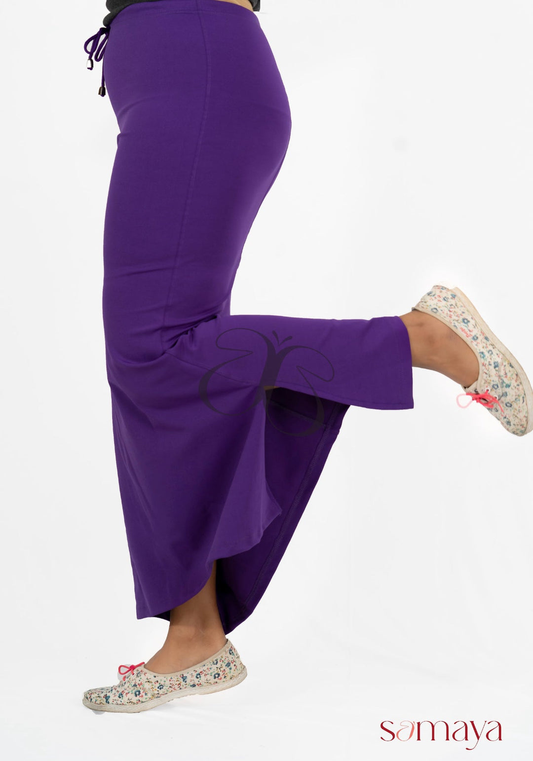 Woman wearing violet Samaya Sareeshaper with four-way stretch and flare hem, paired with floral flats, shown in side pose against white background
