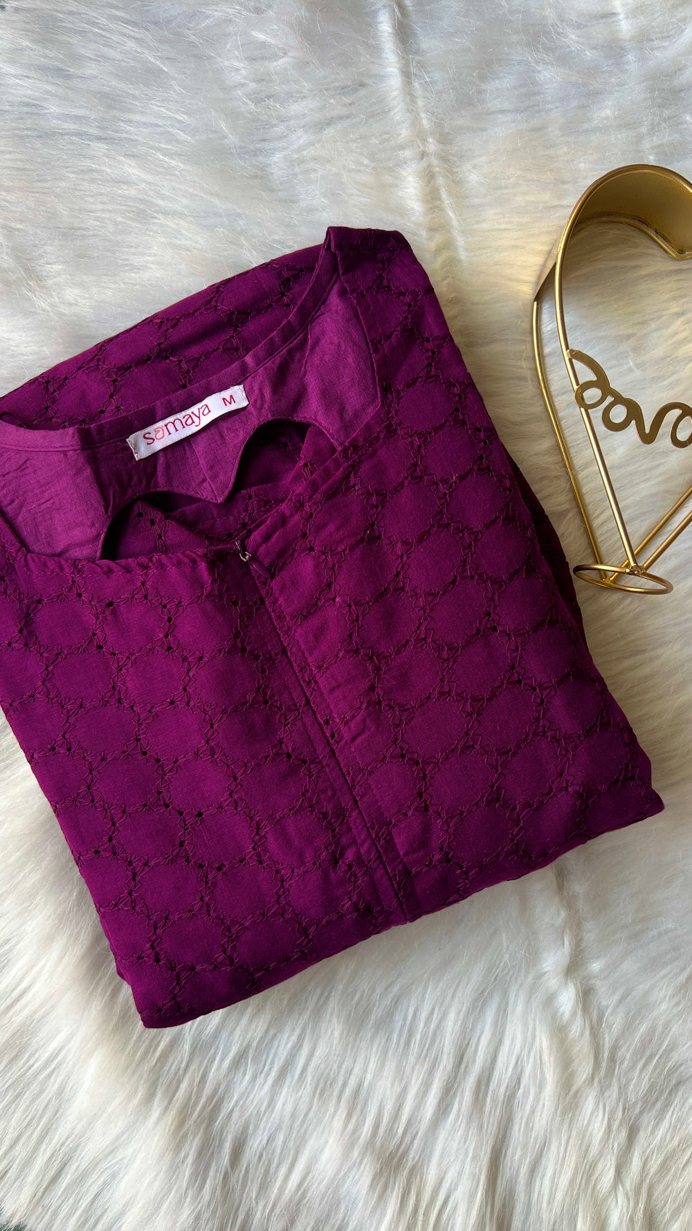 Folded grape-colored cotton hakoba dress with heart neckline and zip opening on white fur background