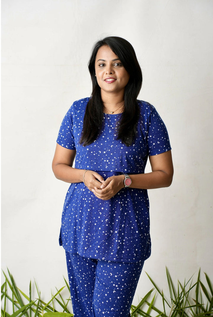 Woman wearing navy blue star printed nursing top and pants feeding pant set