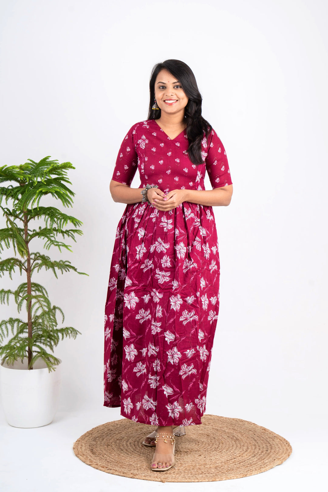 Woman wearing red floral cotton day to night maternity dress with V-neck and elbow sleeves standing indoors