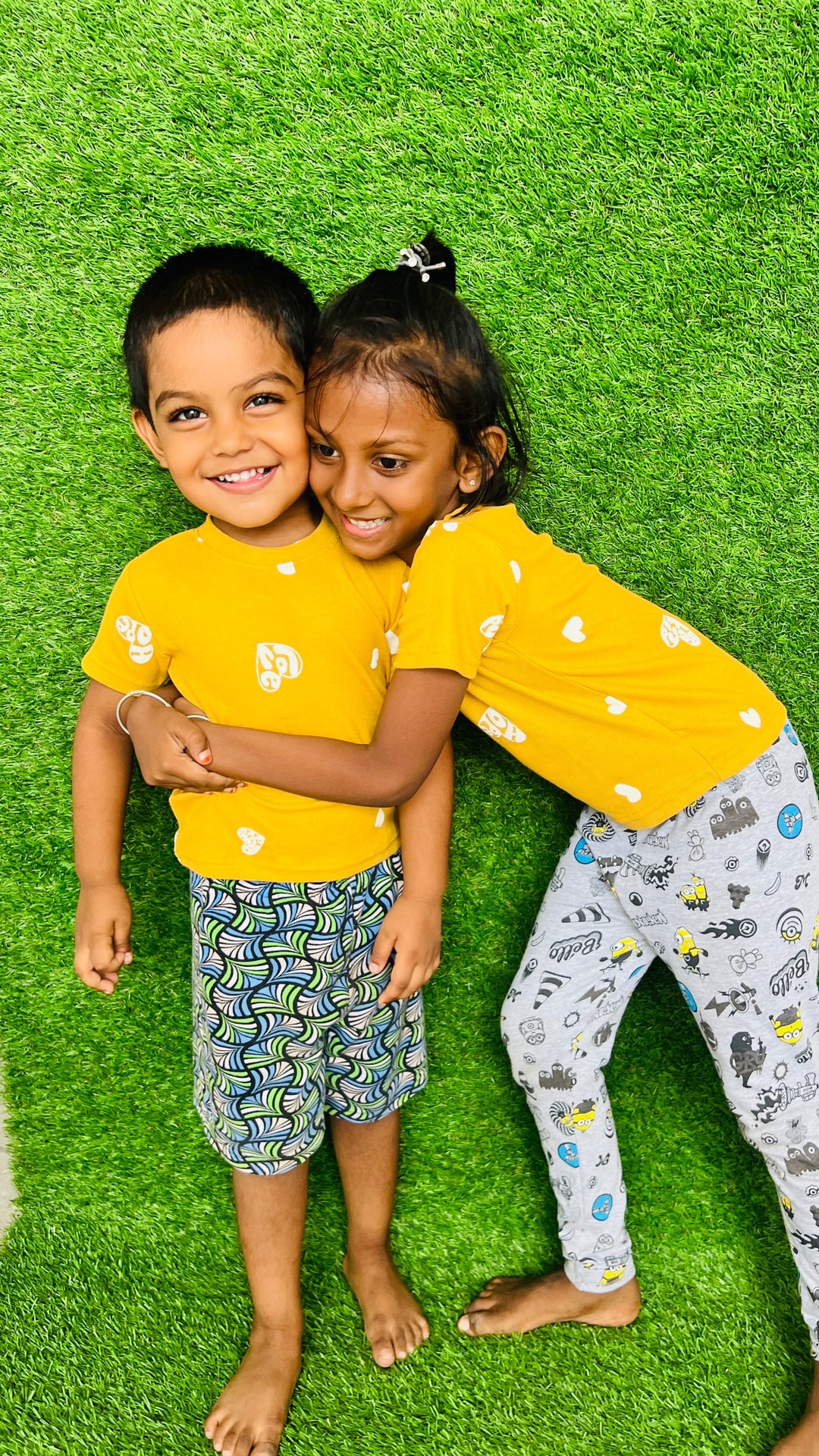 Two kids wearing unisex mustard love t-shirts with ribbed effect and cute prints on green grass background